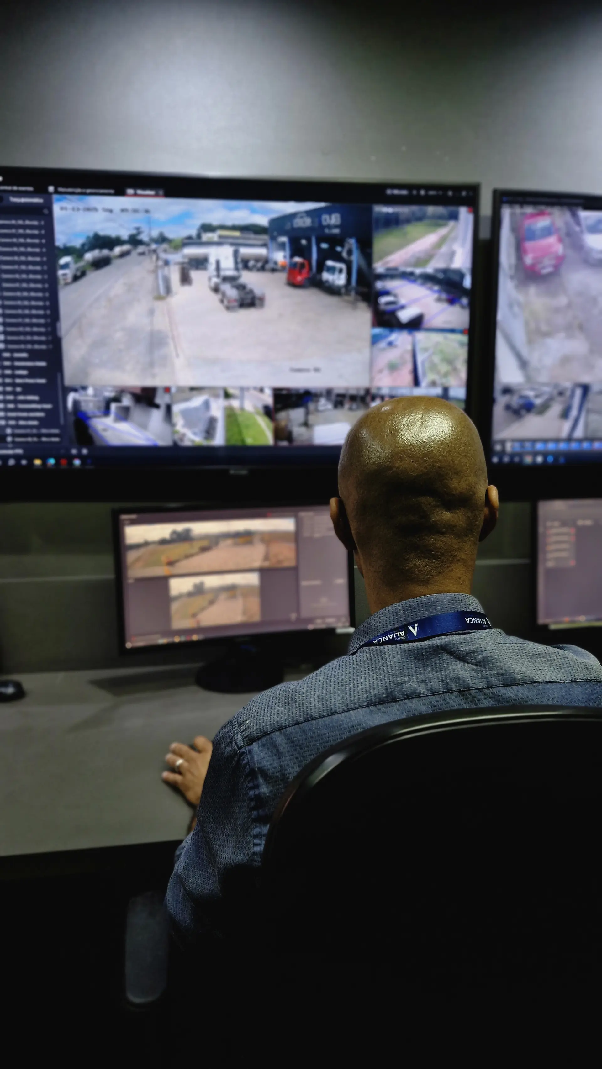 Operador da central de monitoramento diante da parede de monitores