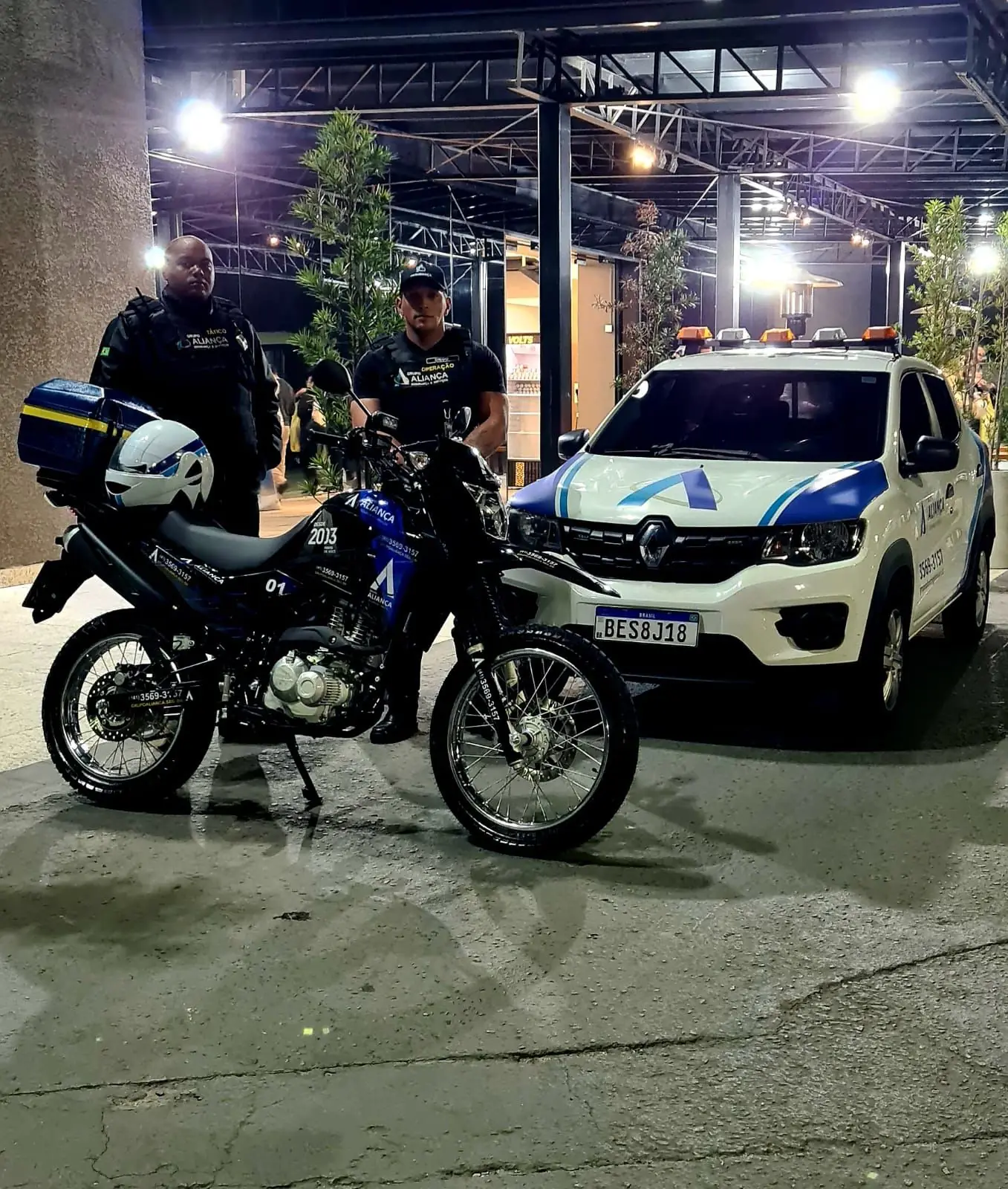 Agentes táticos do Grupo Aliança com moto e viatura à noite
